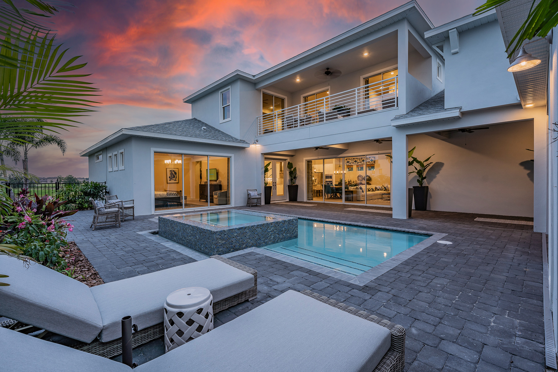 Back patio of a home with a pool at sunset