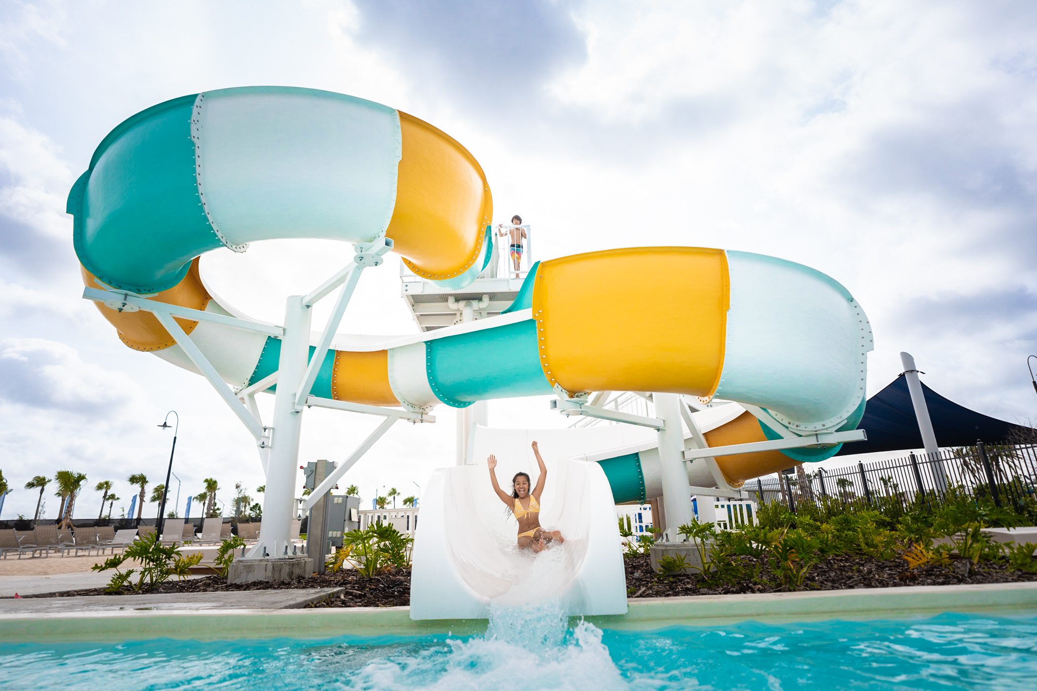 Young woman sliding down a turquoise and yellow water slide