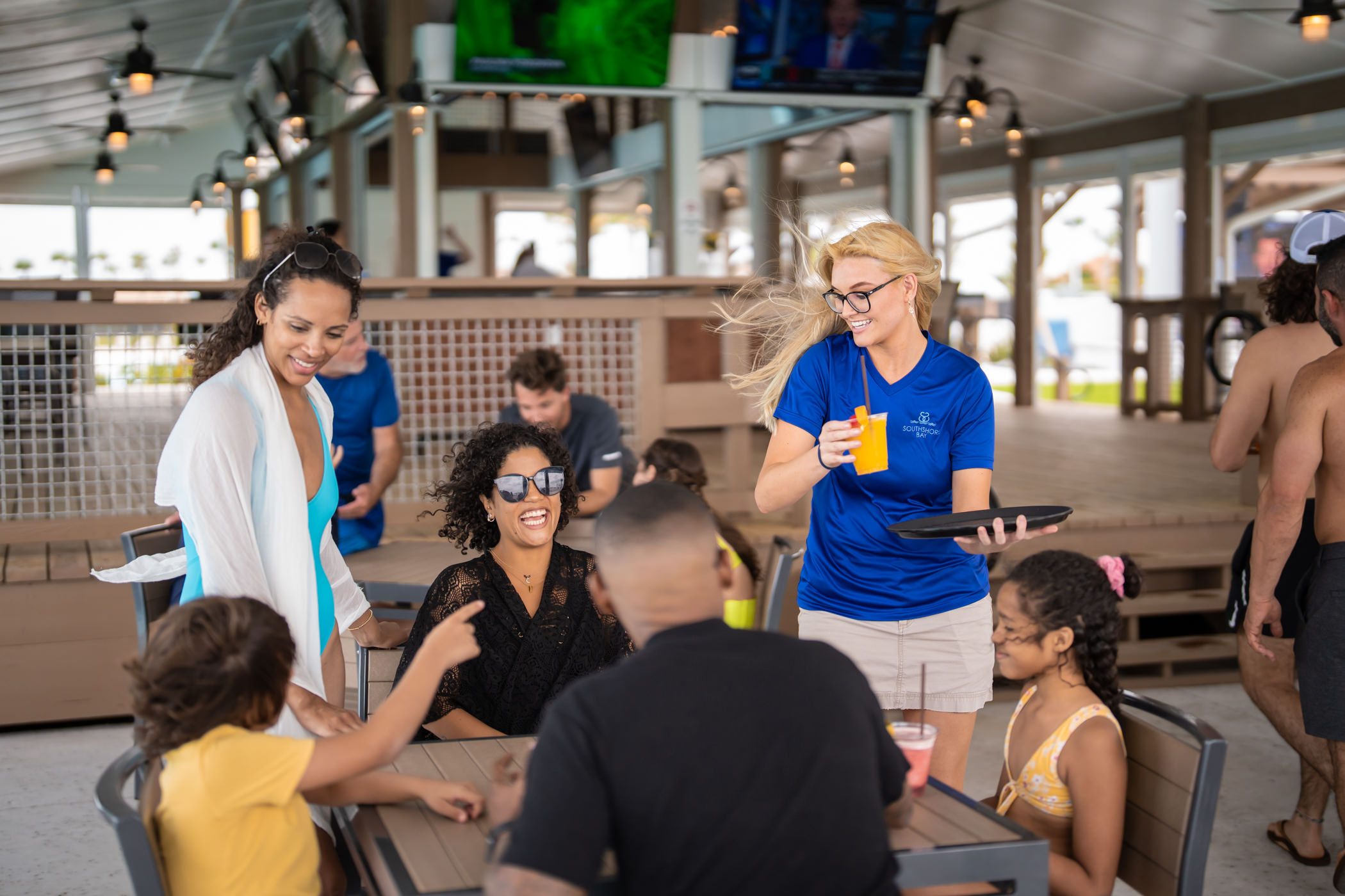 Waitress serving a family drinks at an outdoor table in Southshore Bay