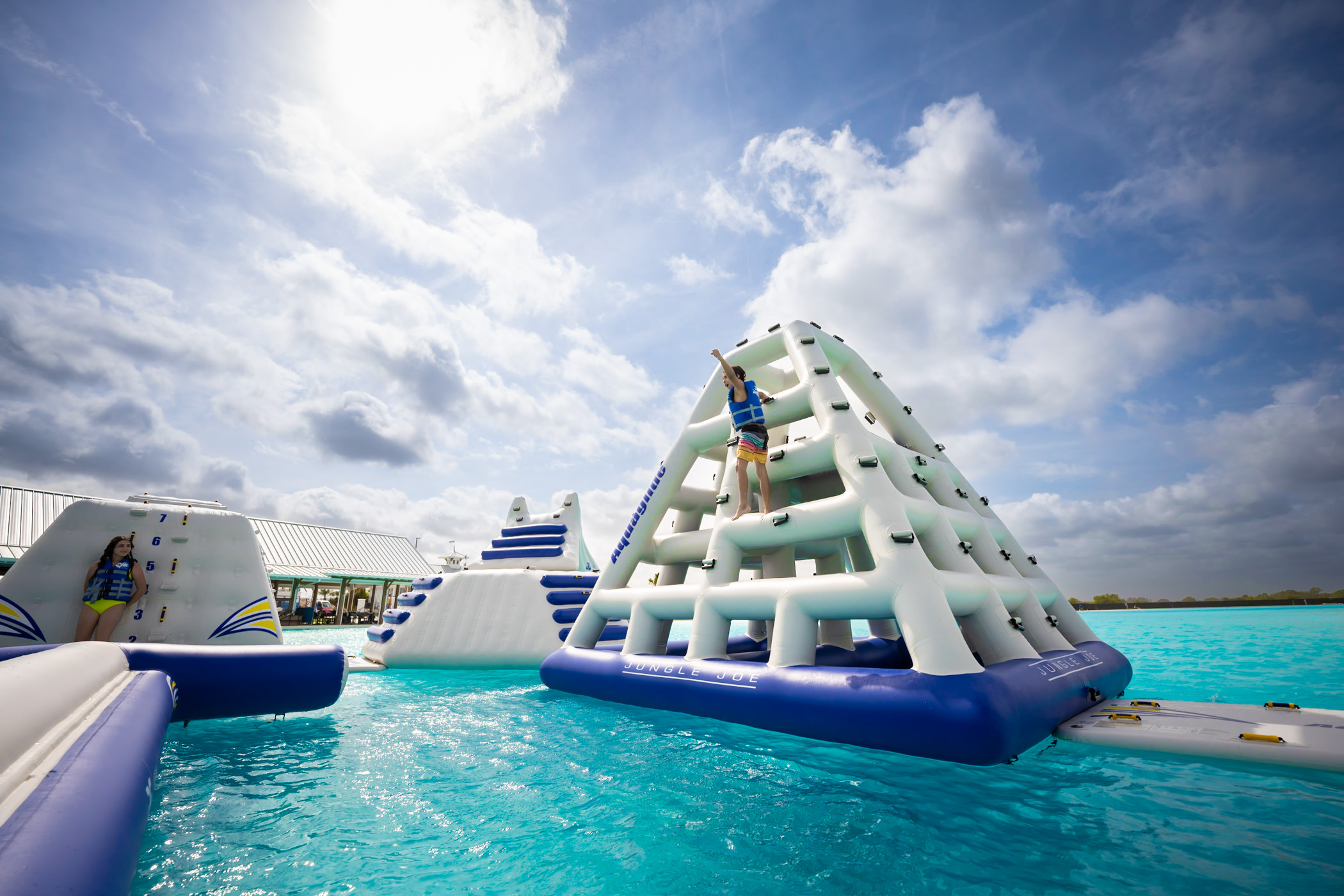 Young boy climbing a pyramid on an inflatable obstacle course on a Metro Lagoon